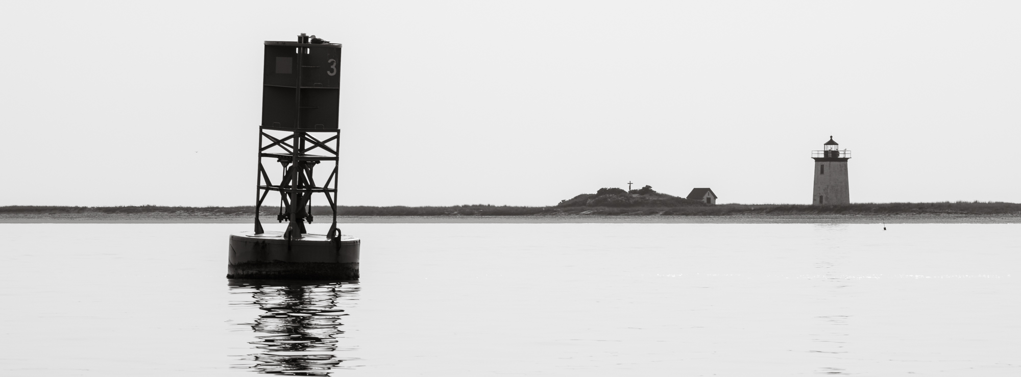 Photograph of marker 23 outside Provincetown harbor with Long Point Light in the background.