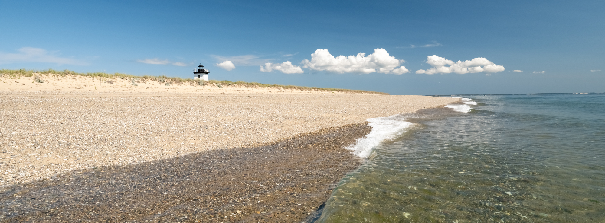 Photographs of waves lapping on the sand of Long Point Beach in Provincetown, MA with Long Point Light in the background.