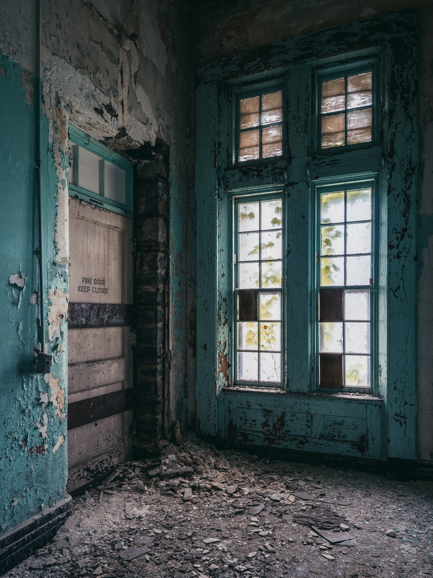 Hospital green walls crumbling plaster fire door and window at Buffalo State Hospital