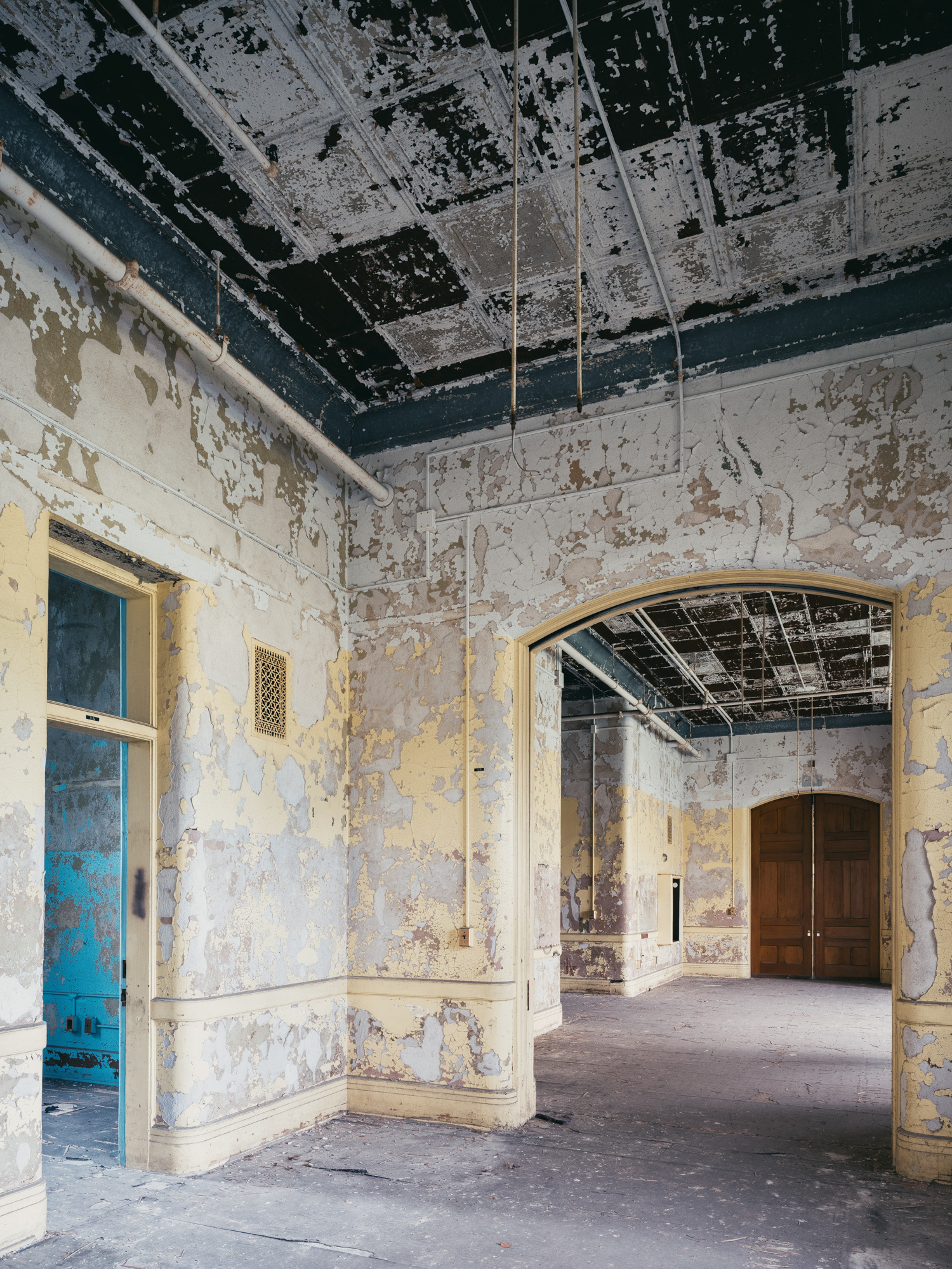 Yellow hallway blue room and wooden doors at Buffalo State Hospital